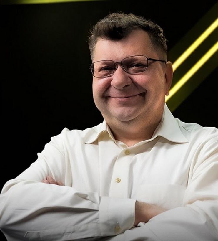 Ręce Zbigniewa Stonogi trzymające mikrofon lub dokumenty, symbolizujące jego działalność publiczną i medialną.