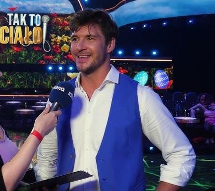 Portret Mikołaja Roznerskiego z bliska, ukazujący jego ciepły i autentyczny wyraz twarzy, z delikatnym, rozmytym tłem.