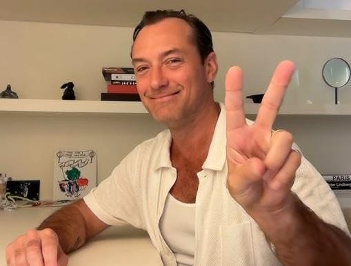 Jude Law na scenie teatralnej, w świetle reflektorów, symbolizujący jego teatralne korzenie i aktorską pasję.