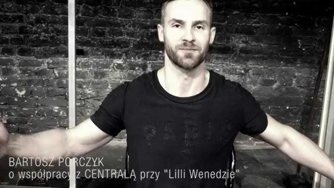 Bartosz Porczyk na scenie teatralnej, w dynamicznej pozie podczas występu, oświetlony reflektorami.