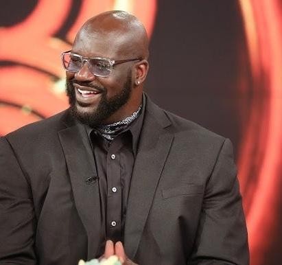 Shaquille O'Neal uśmiechnięty, w swobodnym otoczeniu, symbolizujący jego działalność poza koszykówką.