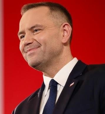 Karol Nawrocki przemawiający na tle historycznych dokumentów.