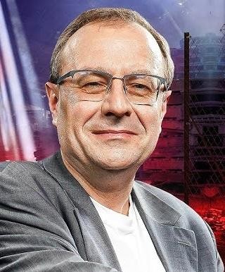 Antoni Dudek podczas wystąpienia medialnego lub prowadzenia programu, w dynamicznym ujęciu.