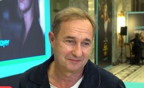 Marek Kalita na scenie teatralnej, w tle elementy scenografii, w trakcie próby lub przed spektaklem.