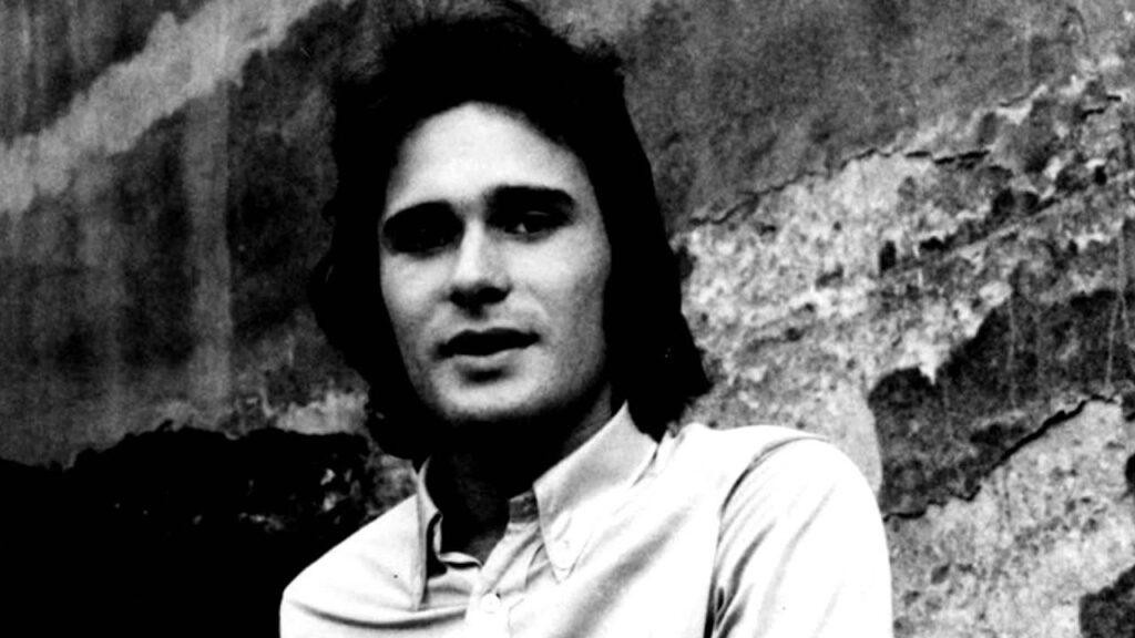 Jerzy Grunwald podczas występu na scenie w młodzieńczych latach, grający na instrumencie lub śpiewający, w stylistyce lat 70.