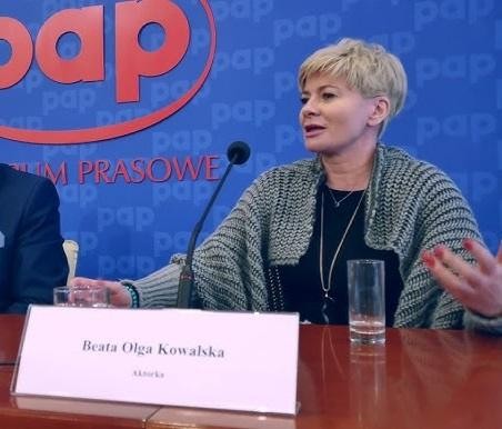Beata Olga Kowalska na scenie teatralnej, w trakcie występu, ukazująca swoją wszechstronność aktorską i sceniczną.